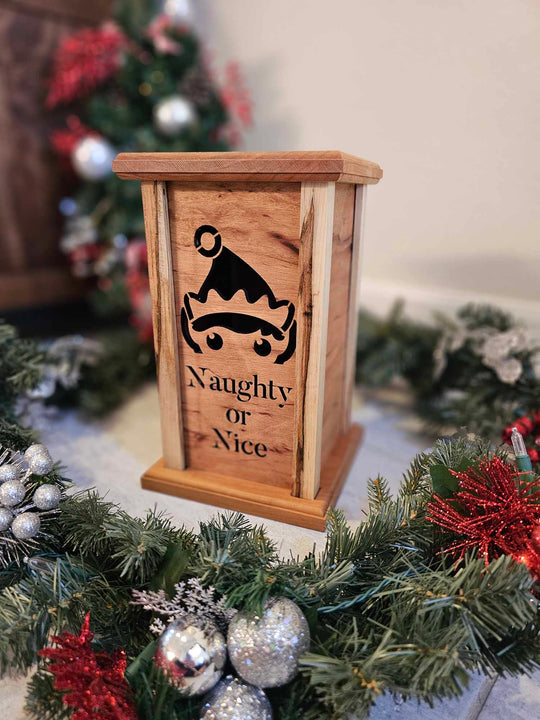 Wooden lantern face depicting a elf and the words naughty or nice.