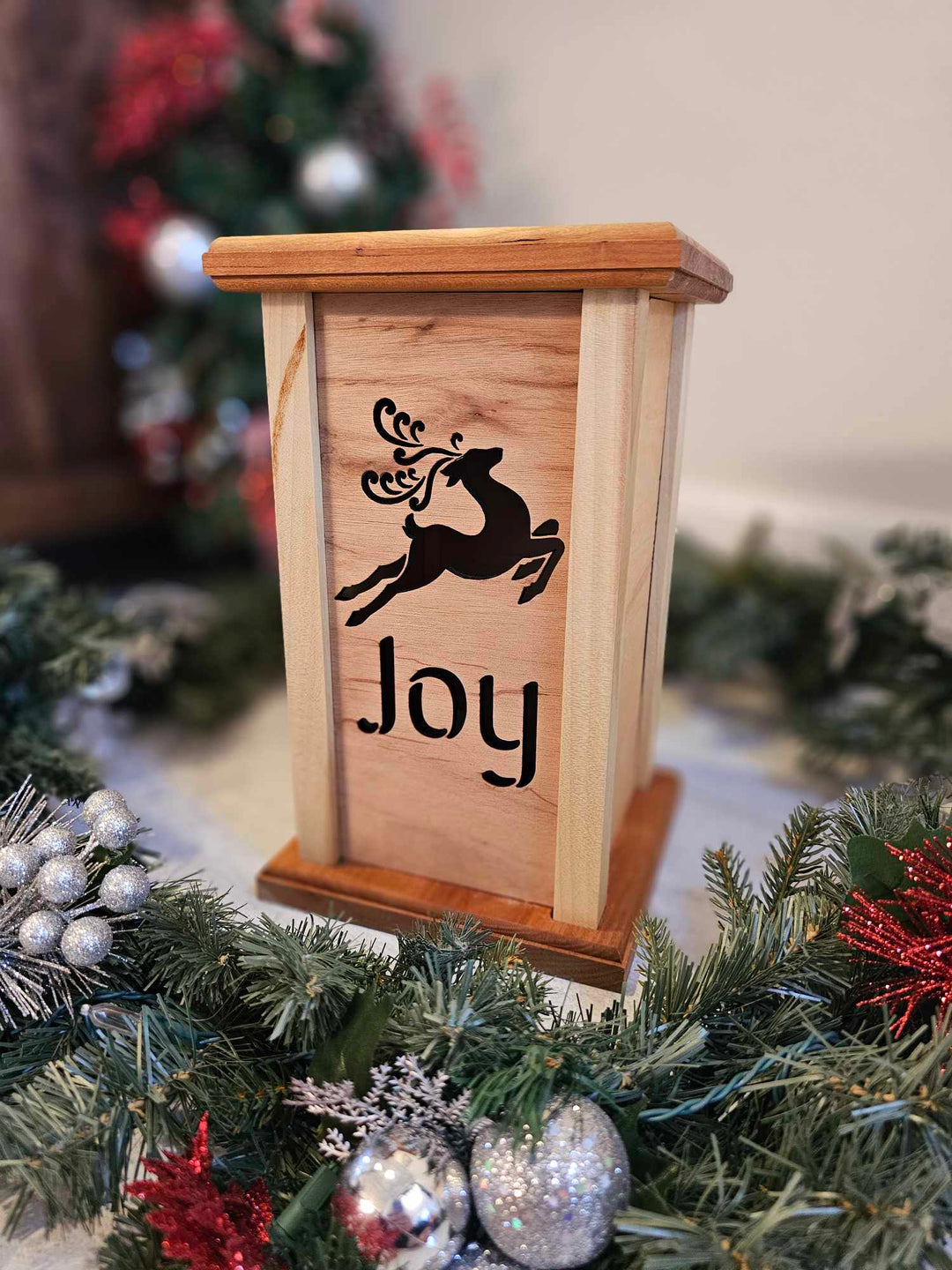 Wooden lantern face depicting a jumping reindeer and the words Joy.