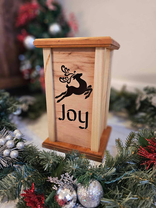 Wooden lantern face depicting a jumping reindeer and the words Joy.