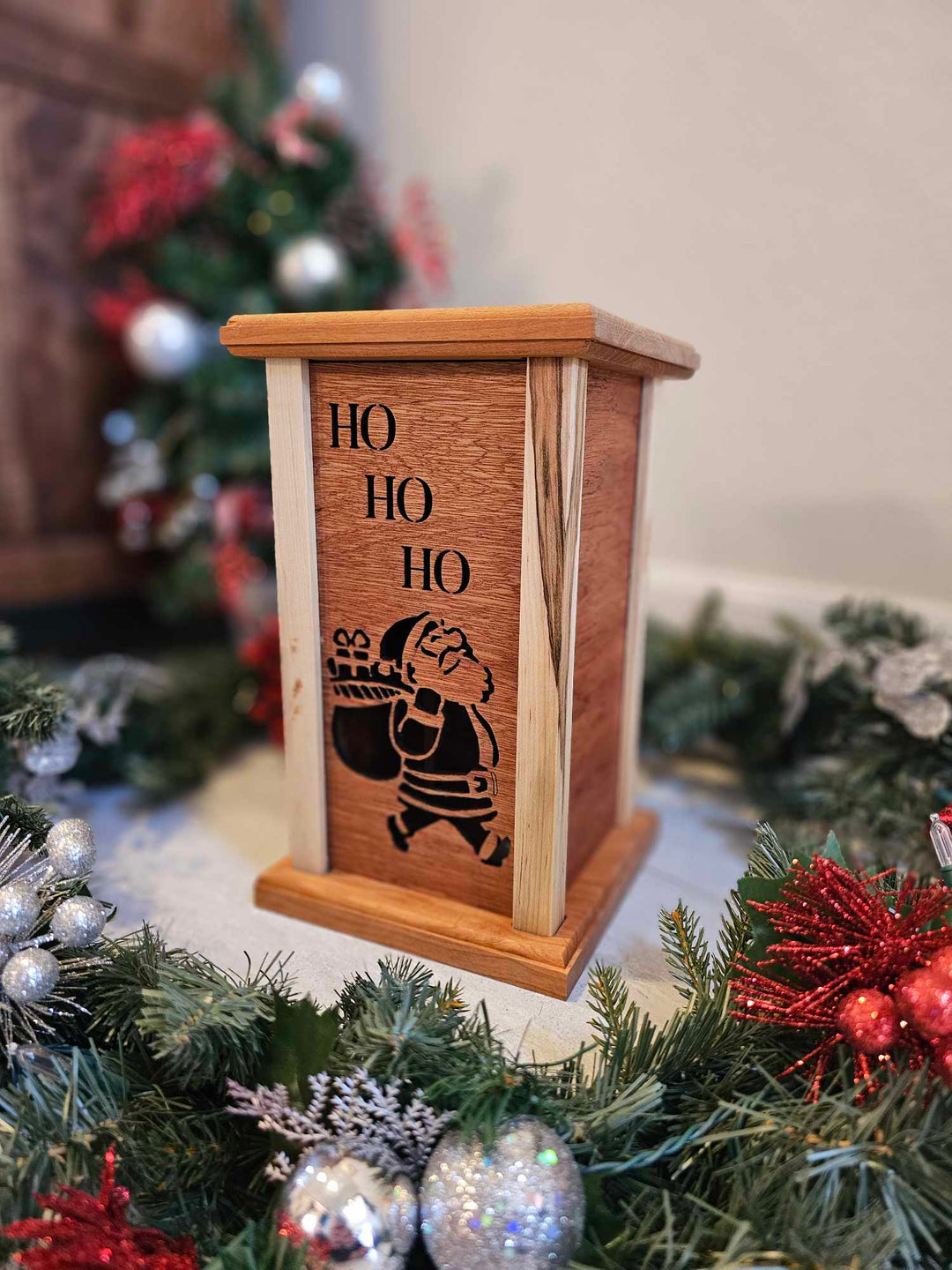 Wooden lantern face showing Santa Claus with a gift bag and the words Ho Ho Ho.