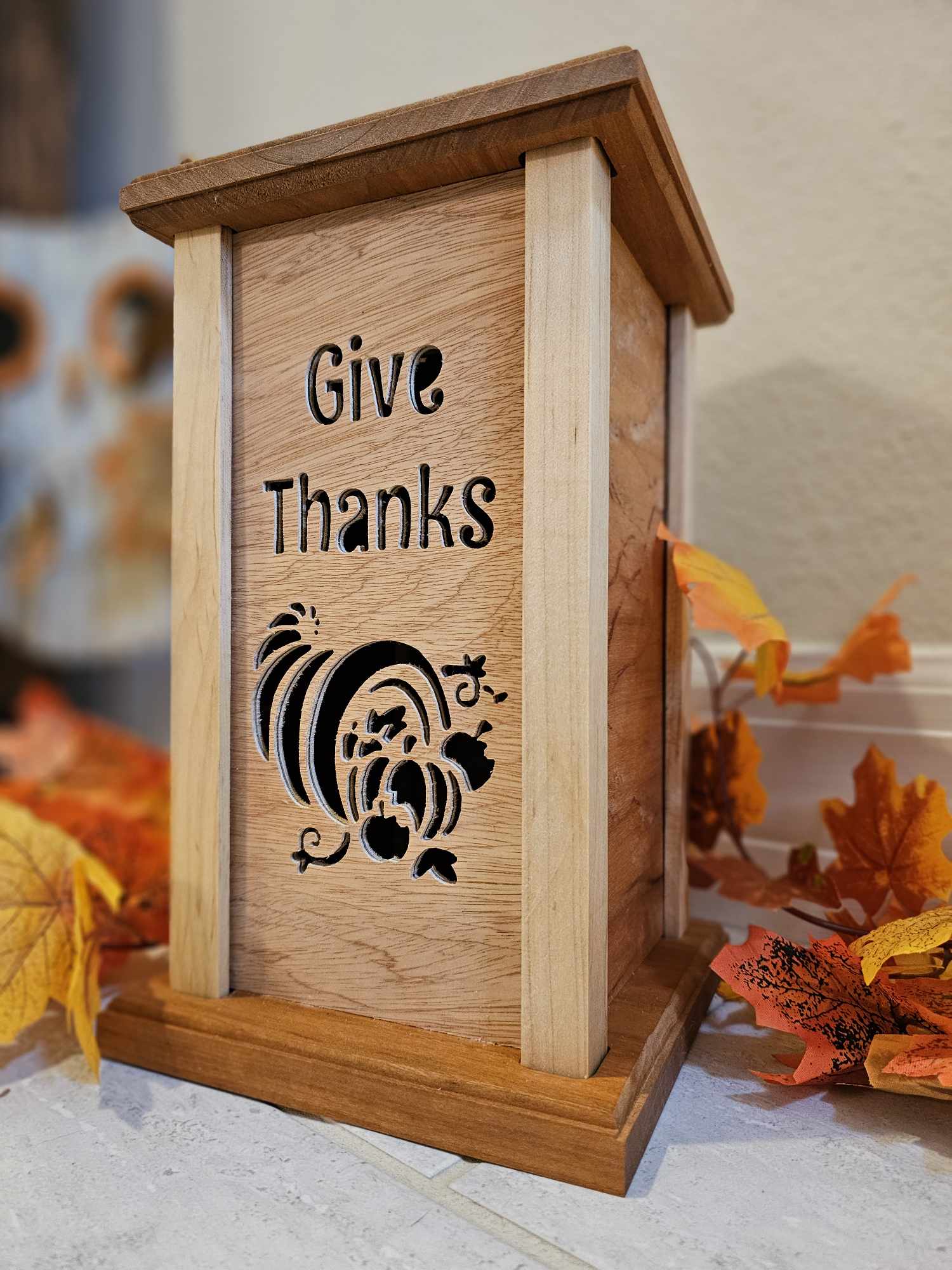 Wooden lantern face depicting a cornucopia and the phrase "Give Thanks".