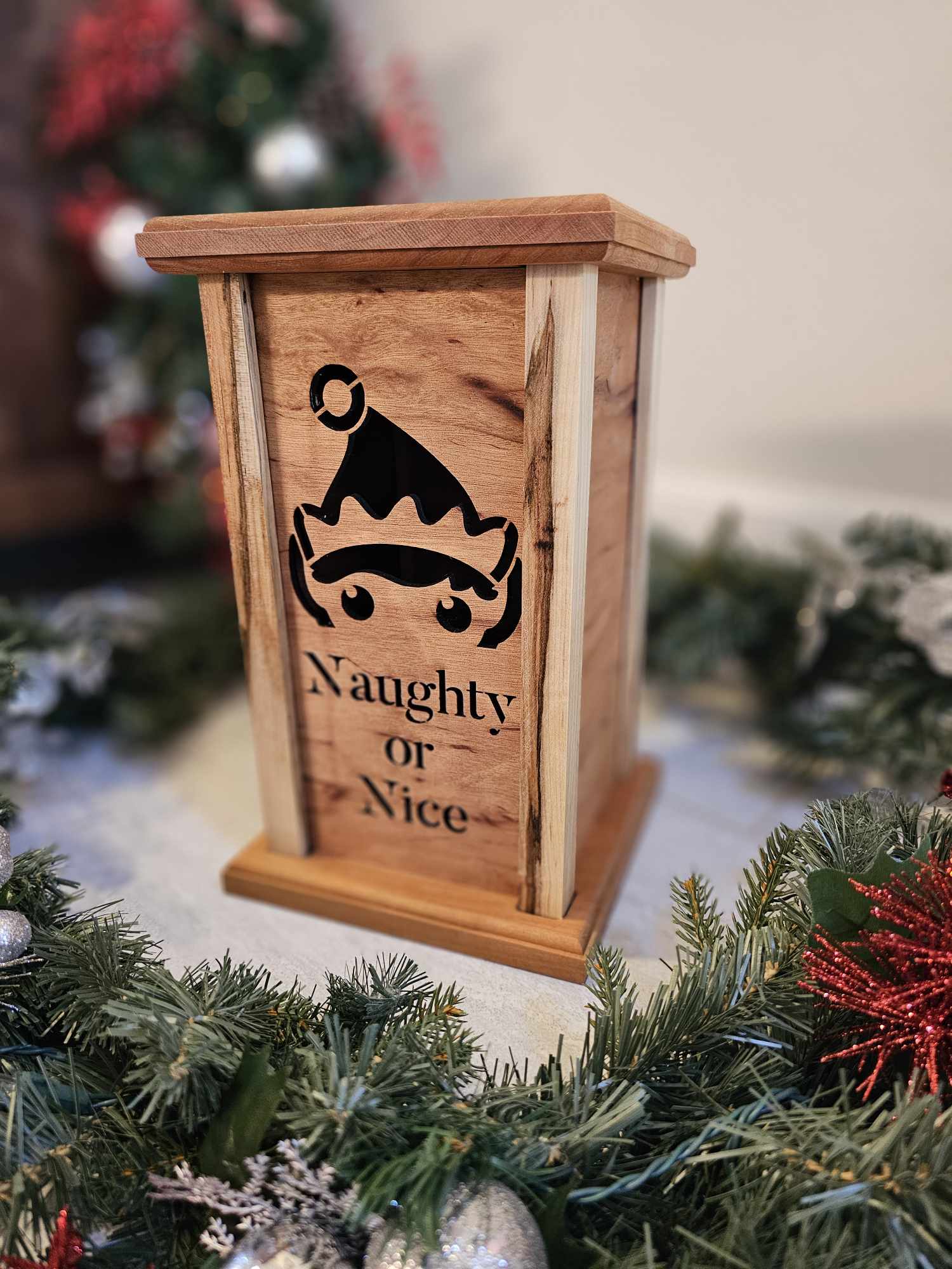 Wooden lantern face depicting a elf and the words naughty or nice.