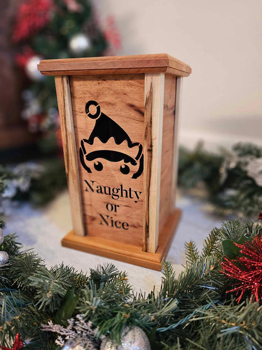 Wooden lantern face depicting a elf and the words naughty or nice.