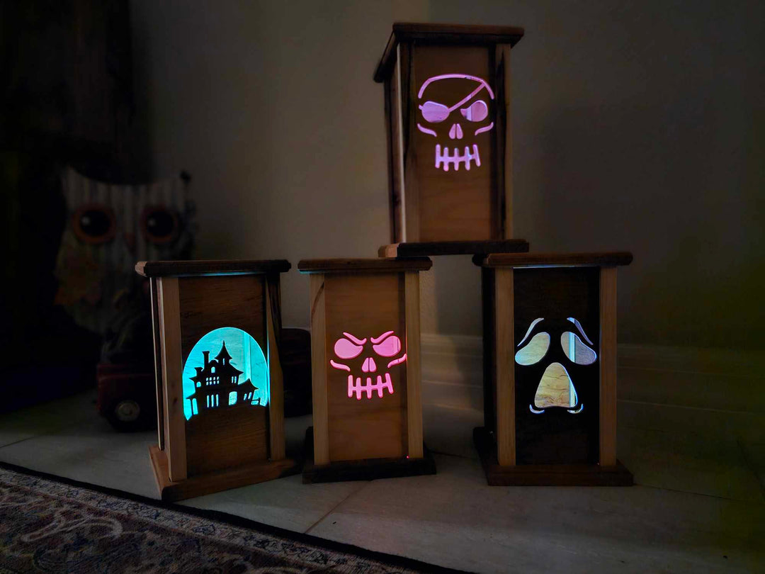 Four wooden lanterns with lantern faces depicting a haunted house, skull face, pirate skull, and moaning ghost face.