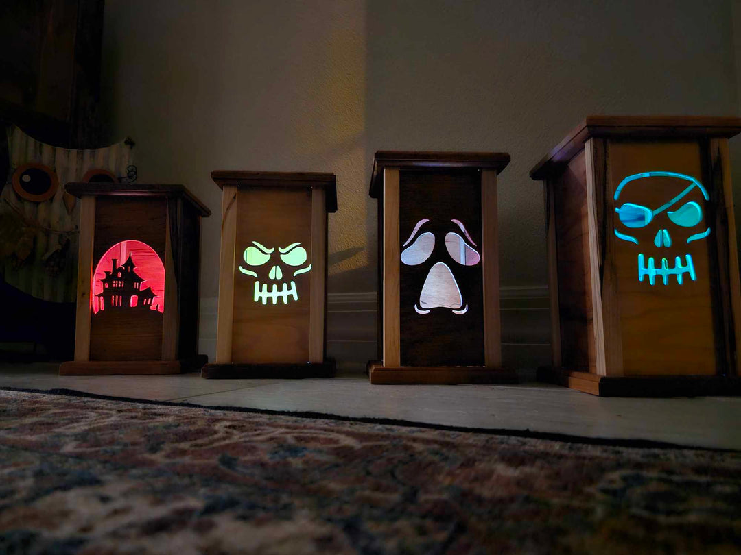 Four wooden lanterns with lantern faces depicting a haunted house, skull face, moaning ghost face, and pirate skull.