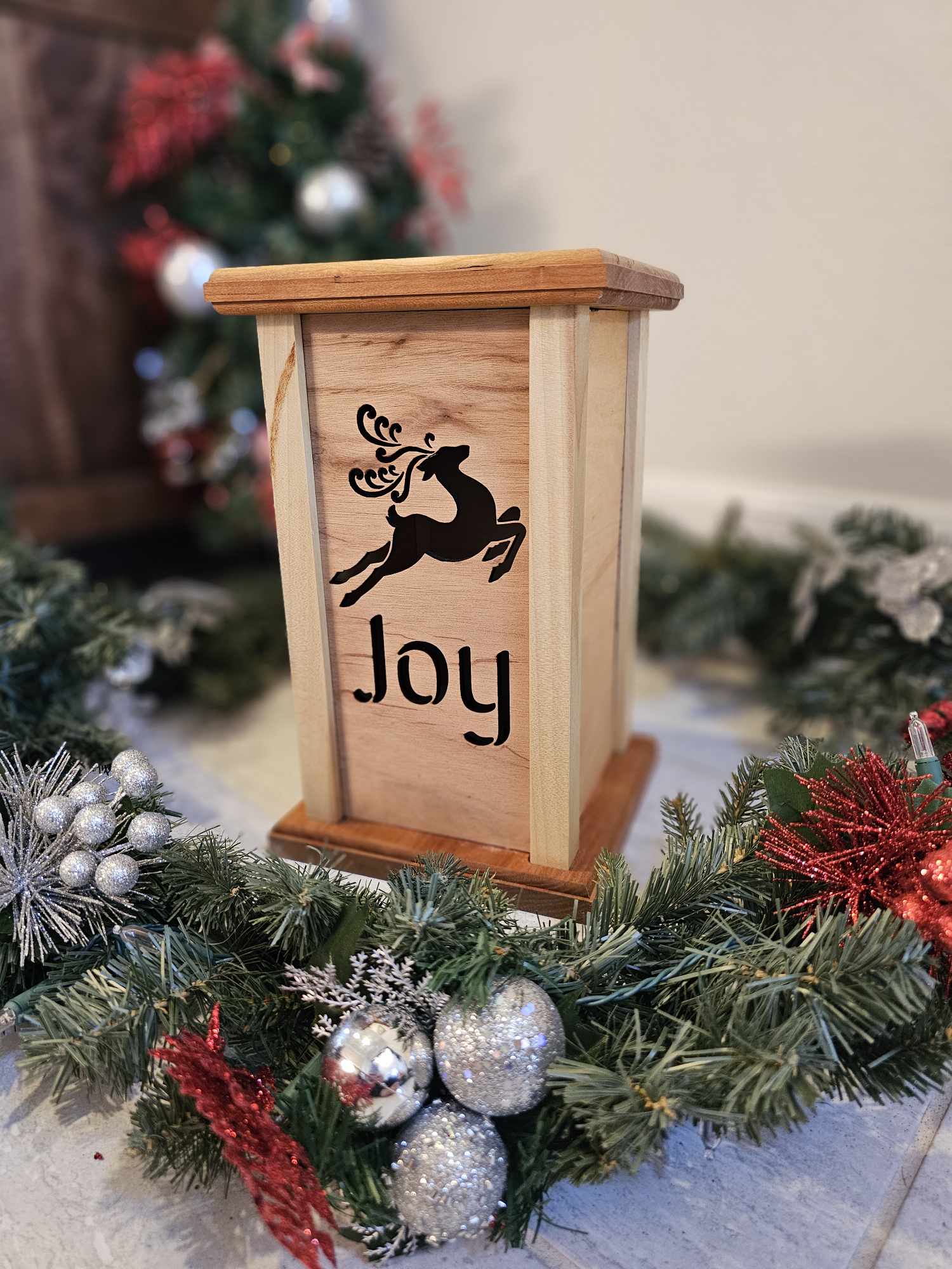 Wooden lantern face depicting a jumping reindeer and the words Joy.