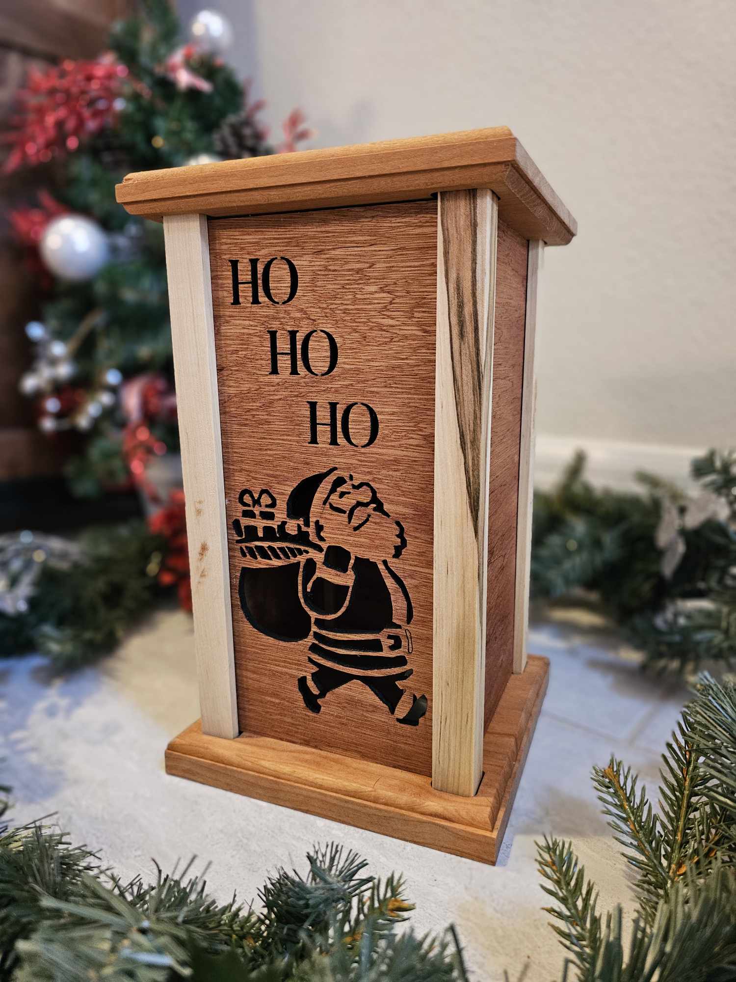 Wooden lantern face showing Santa Claus with a gift bag and the words Ho Ho Ho.