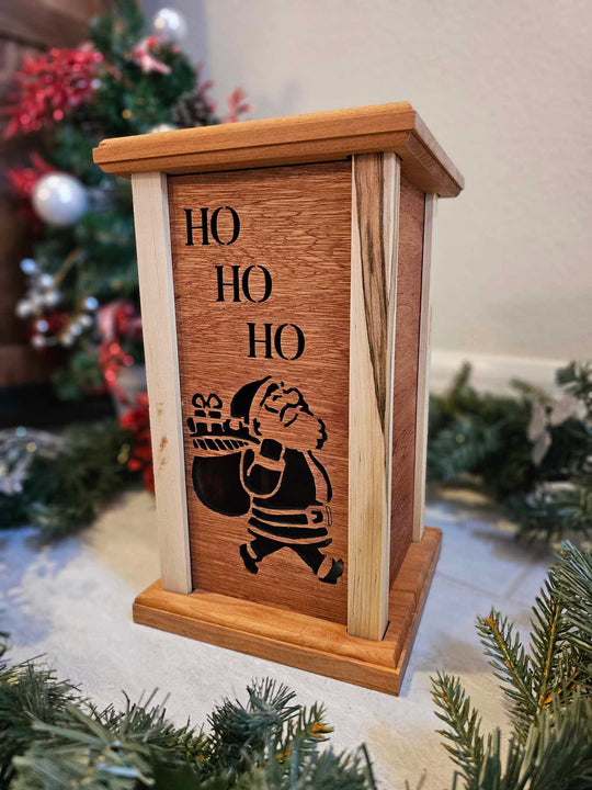 Wooden lantern face showing Santa Claus with a gift bag and the words Ho Ho Ho.