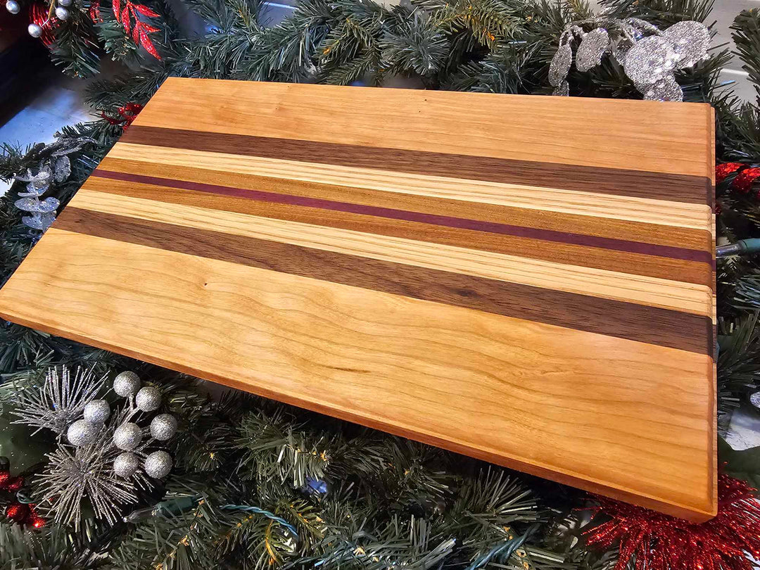 A charcuterie board with stripes of cherry, walnut, oak, afromasia, and purple heart.
