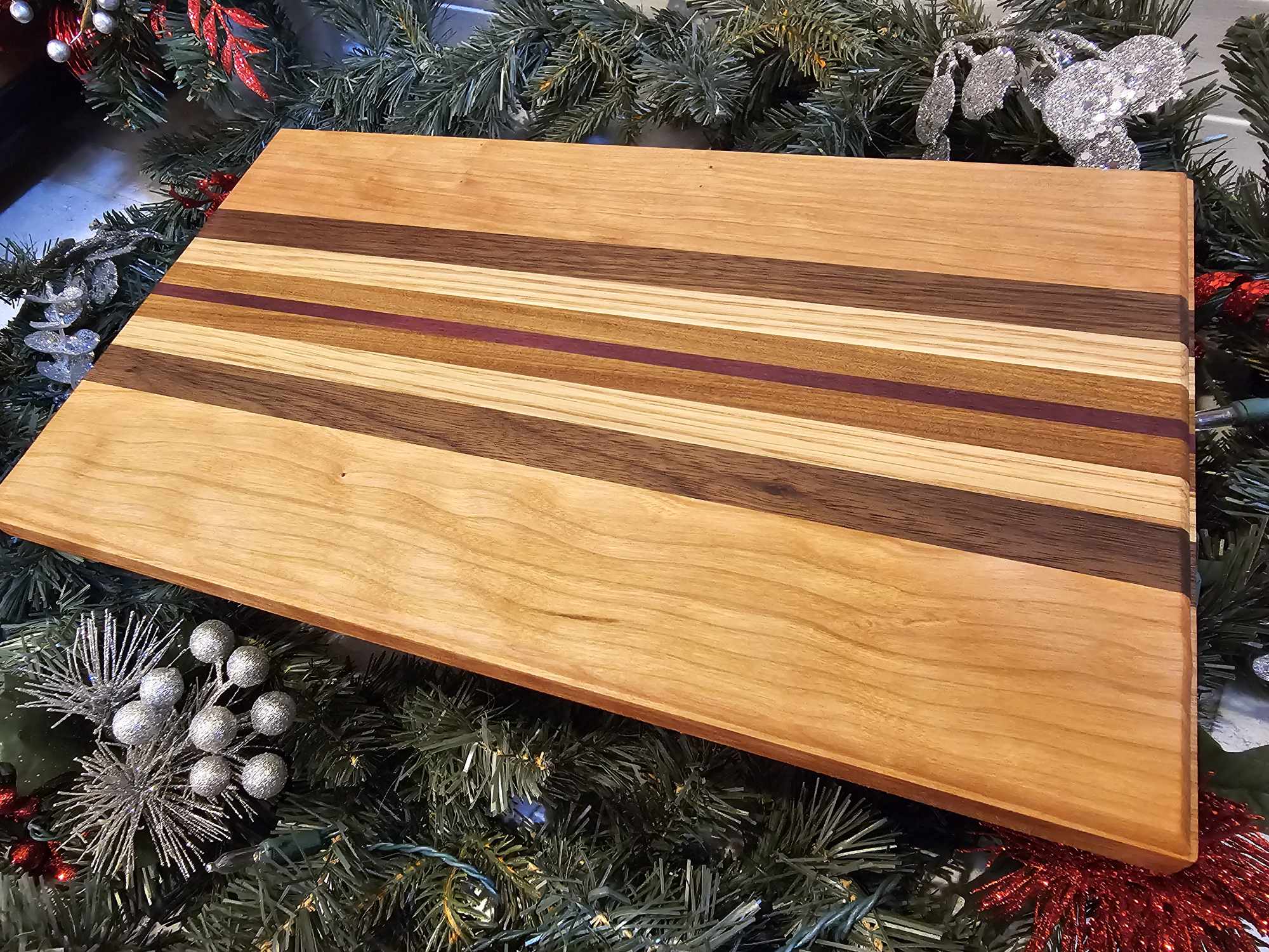 A charcuterie board with stripes of cherry, walnut, oak, afromasia, and purple heart.