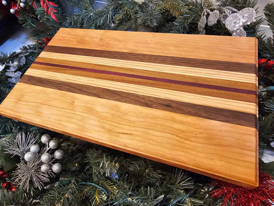 A charcuterie board with stripes of cherry, walnut, oak, afromasia, and purple heart.
