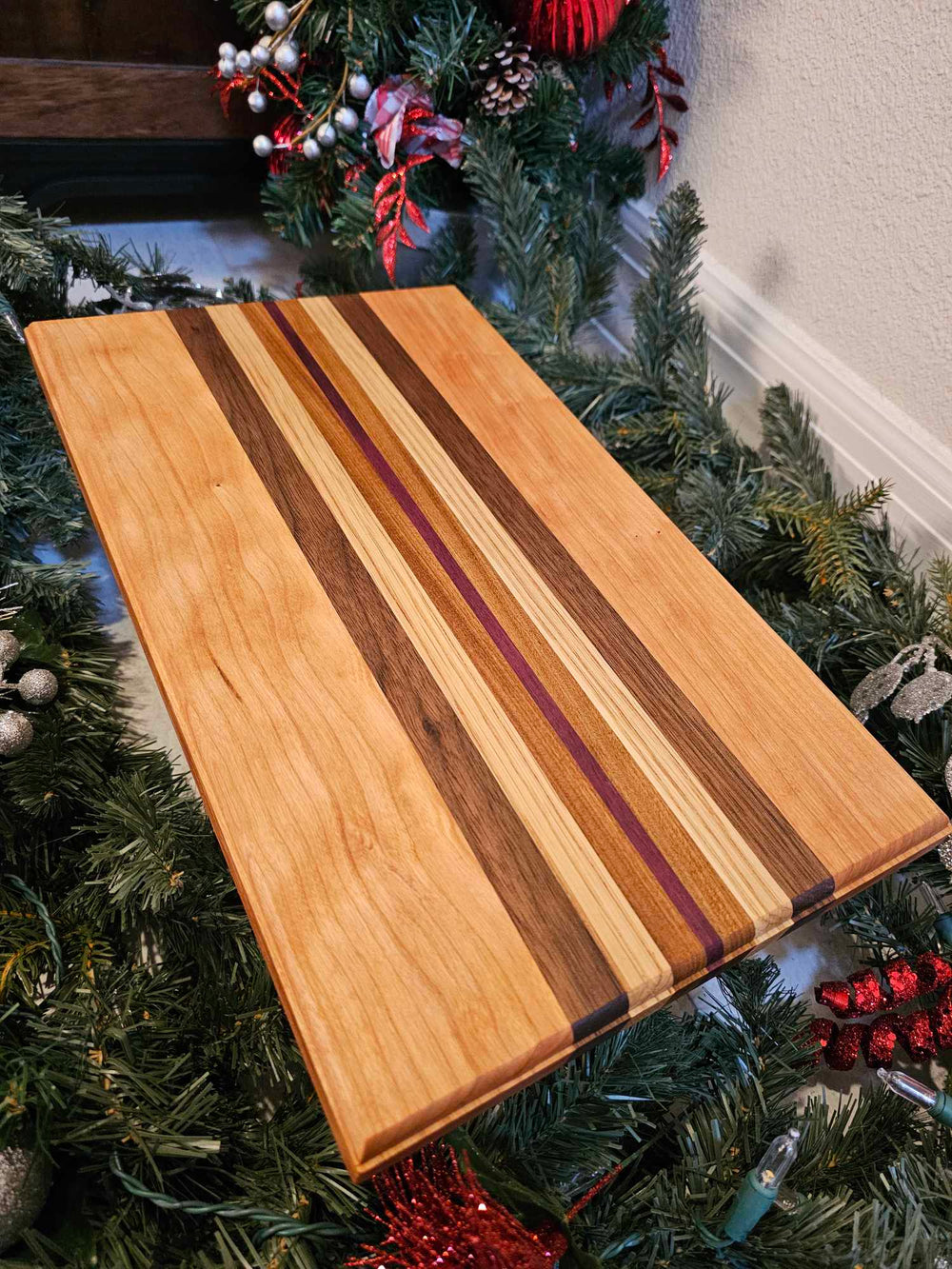A charcuterie board with stripes of cherry, walnut, oak, afromasia, and purple heart.