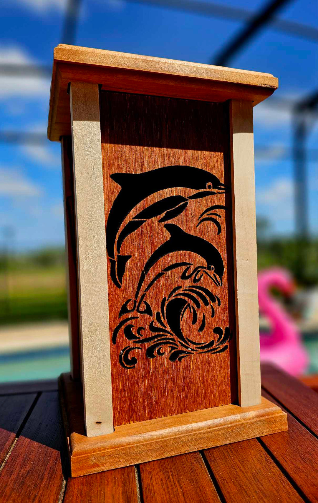 Wooden lantern face depicting two dolphins jumping above waves.