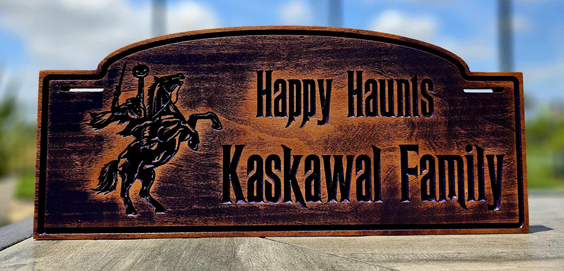 Wooden stroller sign depciting a headless horseman with the words "Happy Haunts" and "Kaskawal Family".